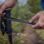 How to hold trekking poles correctly with hand threading through wrist strap from below demonstrating proper grip technique