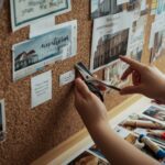 Person creating vision boards with magazine clippings and inspirational images on cork board