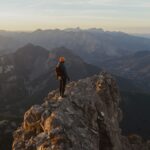 Courage to face fear at mountain summit with climber overlooking vast landscape