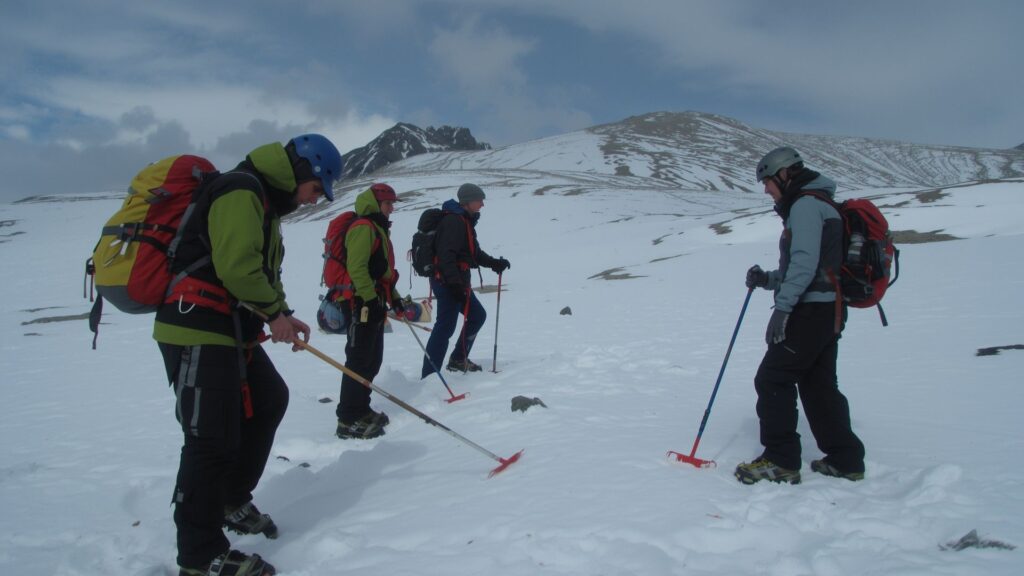 Winter hiking gear training session with guide teaching crampon and ice axe techniques