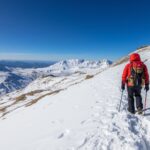 Winter hiking tips guide showing equipped hiker on snowy Irish mountain trail with proper gear and ice axe