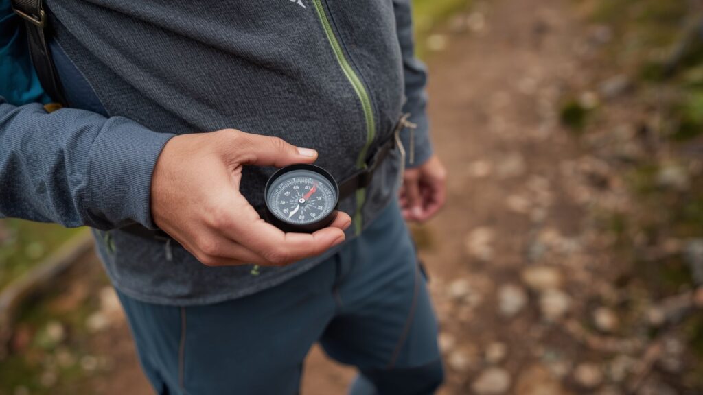 Using a compass correctly by holding it level between waist and chest height on a hiking trail