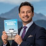 Pat Falvey holds Accidental Rebel autobiography with Kerry mountains behind him