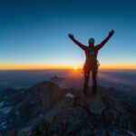 Pat Falvey achieving your goals at mountain summit with raised arms celebrating success in mountaineering expedition