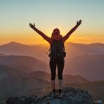 Top 5 trekking tips for women - female hiker celebrating summit success on mountain peak