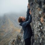 Hiker wearing softshell jacket climbing Carrauntoohil rocky terrain in Kerry Ireland